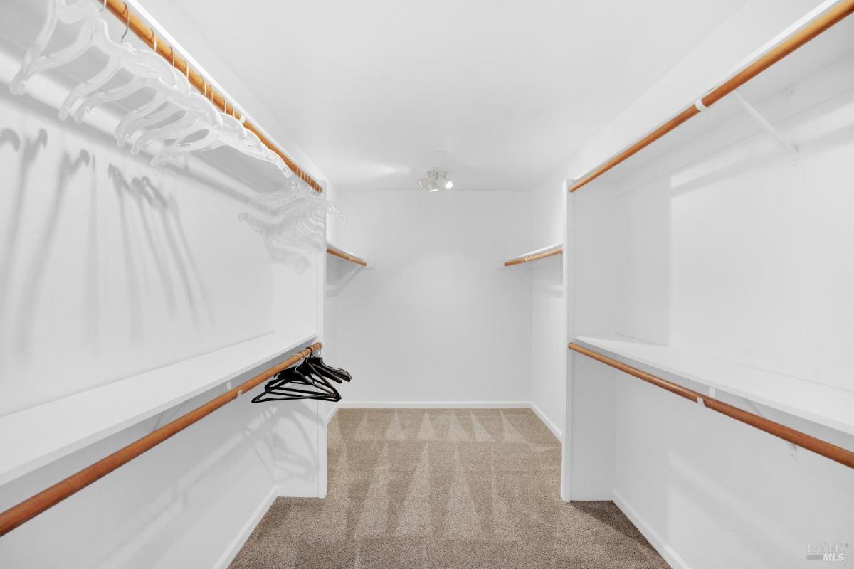 Walk-in closet with wooden shelves and hanging racks.