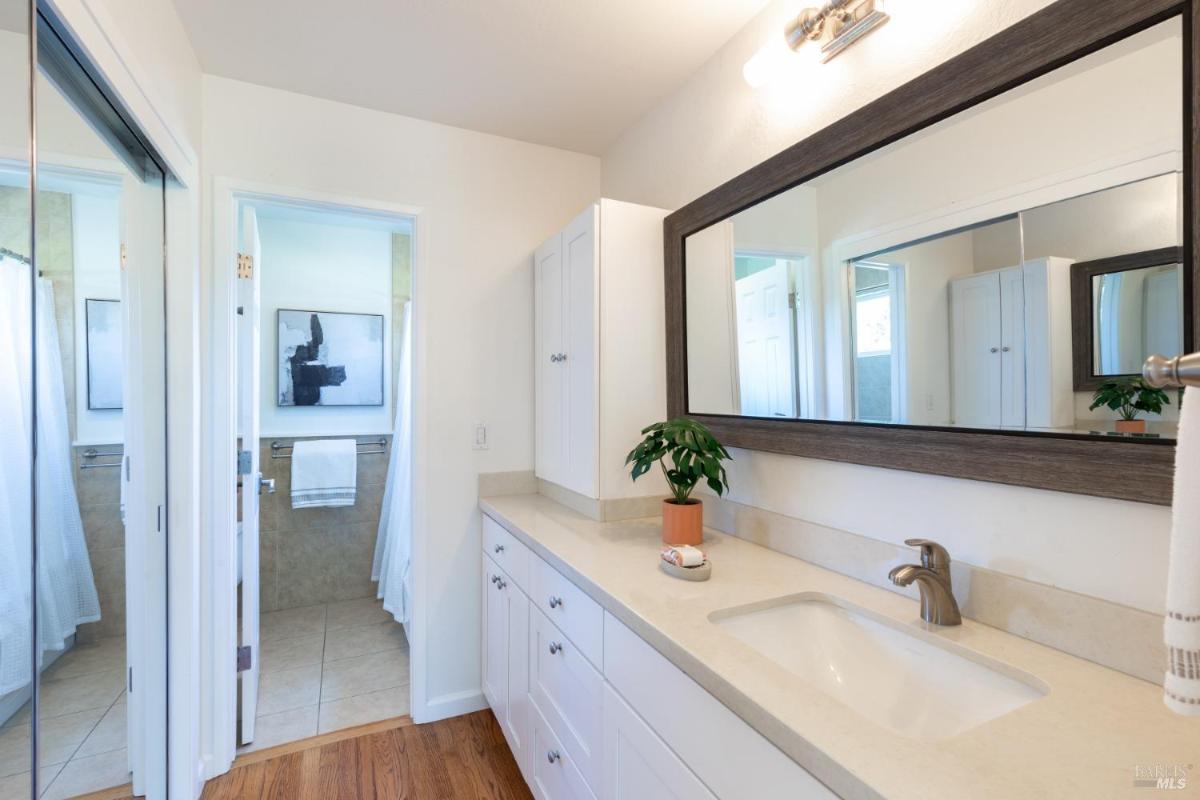 A bathroom with a large mirror, double vanity, and wood cabinetry.