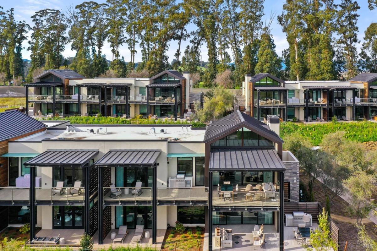 Modern homes with glass balconies surrounded by tall trees and greenery.