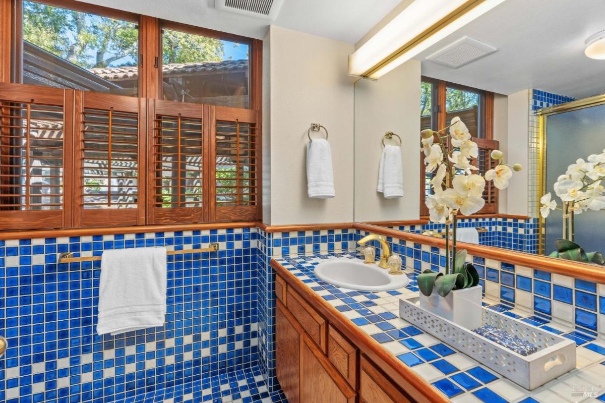 A bathroom with blue tile accents and a wood vanity with a mirror and towel rack.