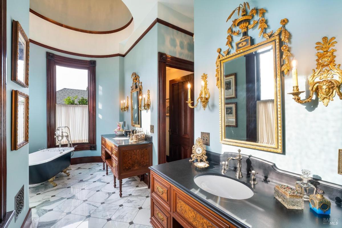 A bathroom with a freestanding bathtub, decorative vanity, and arched ceiling.