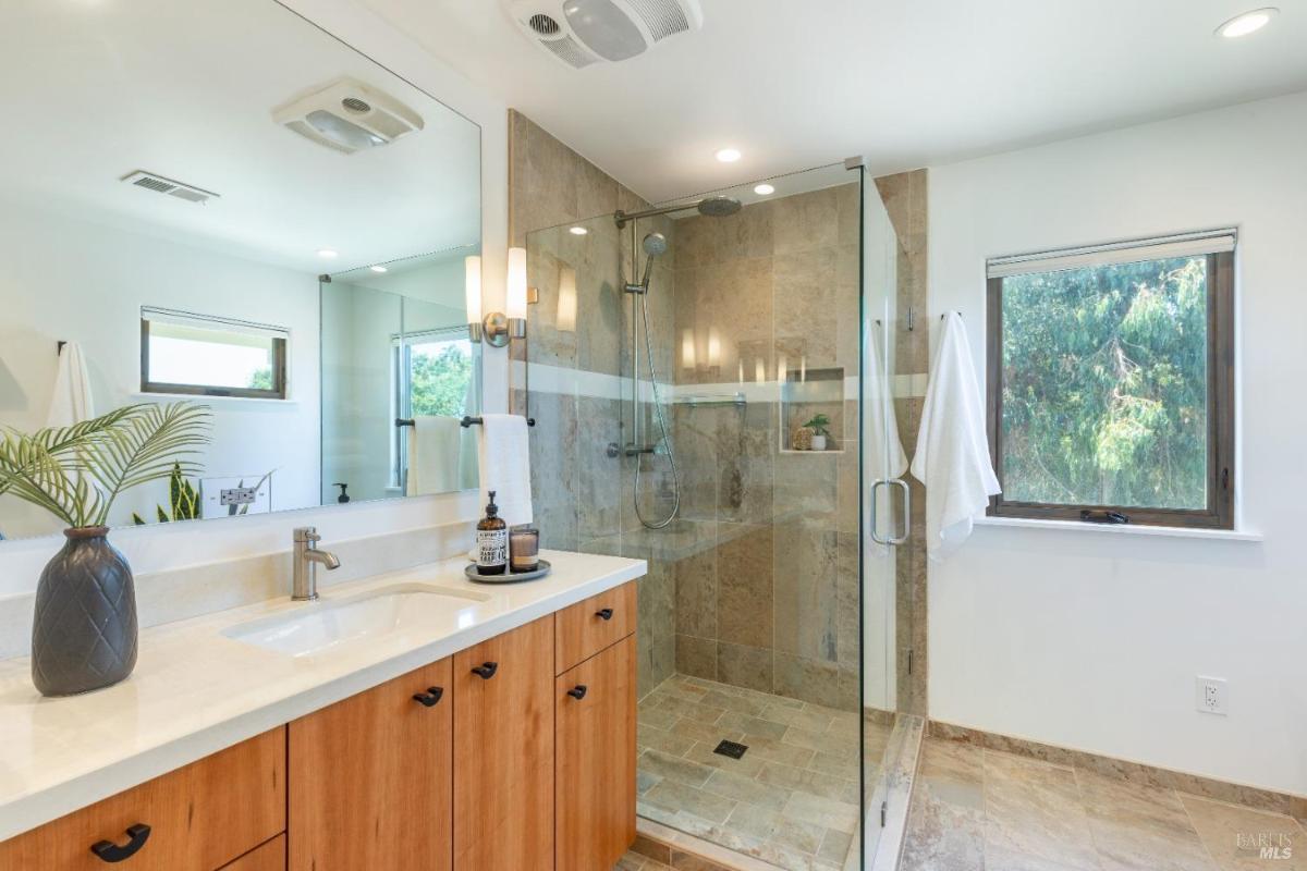 A bathroom with a glass-enclosed shower and a white vanity.