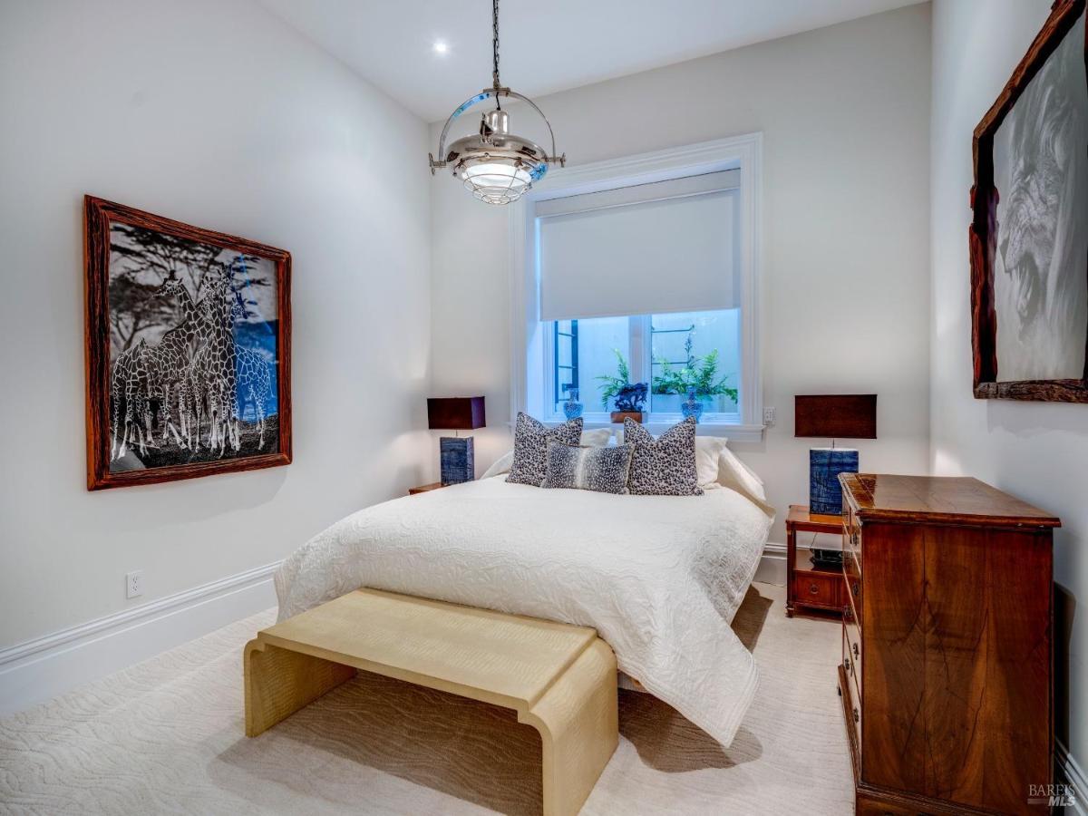 A bedroom featuring a neutral bed, wooden furniture, and giraffe-themed wall art.