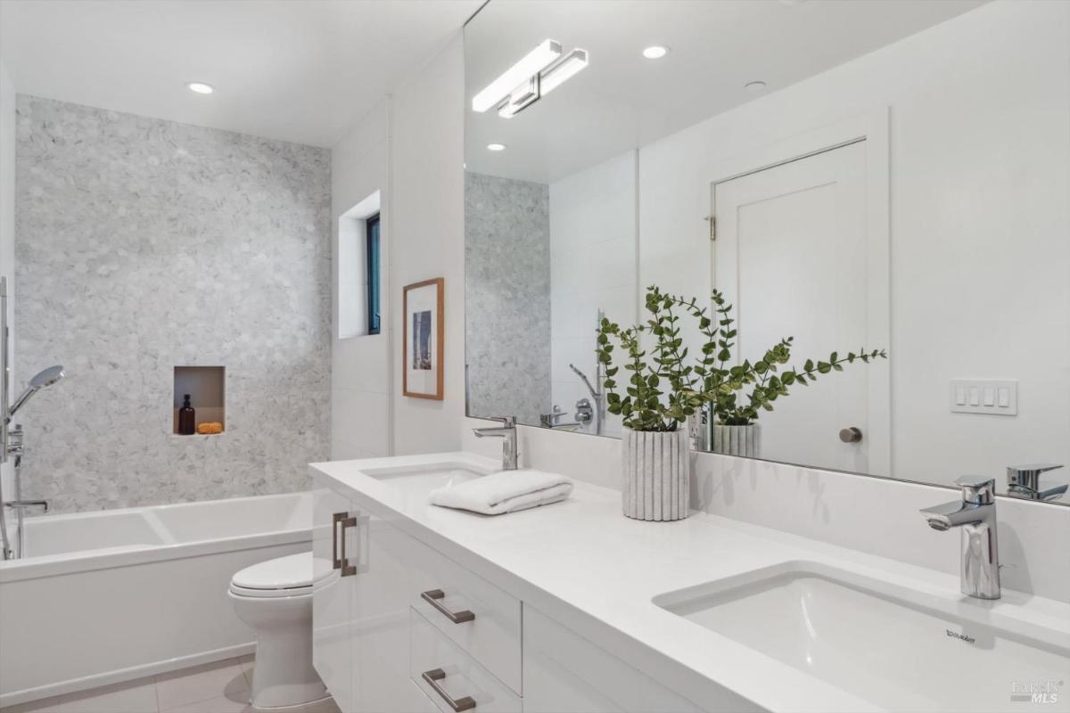 Bathroom with tub and niche, featuring a double vanity, a bathtub, and a shower niche with toiletries.