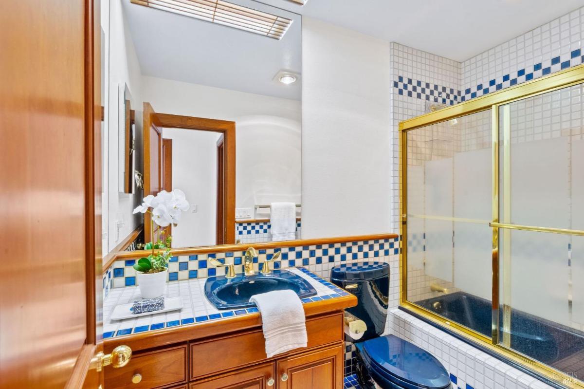 A bathroom featuring a blue sink and gold hardware with a glass shower door.