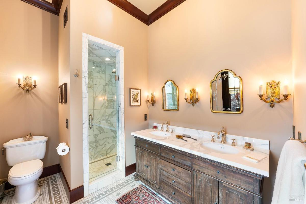 A bathroom with a shower, dual sinks, and beige walls.