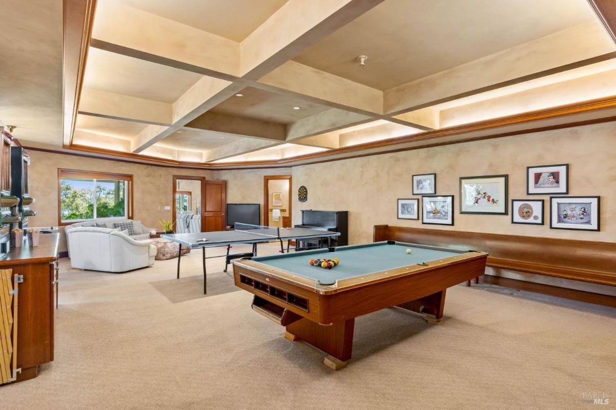 A game room with a pool table, ping pong table, and framed wall decor.