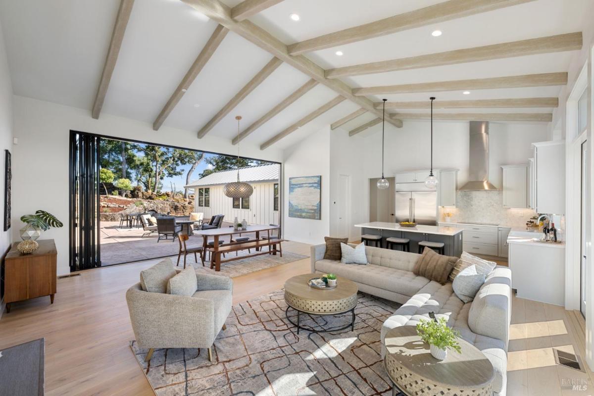 An open living room with exposed ceiling beams and a view to the outdoor patio.