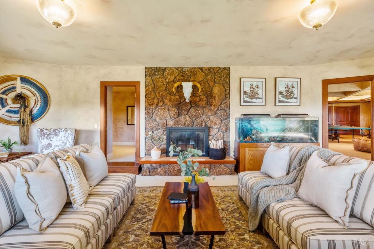 A living room with a stone fireplace and seating area.