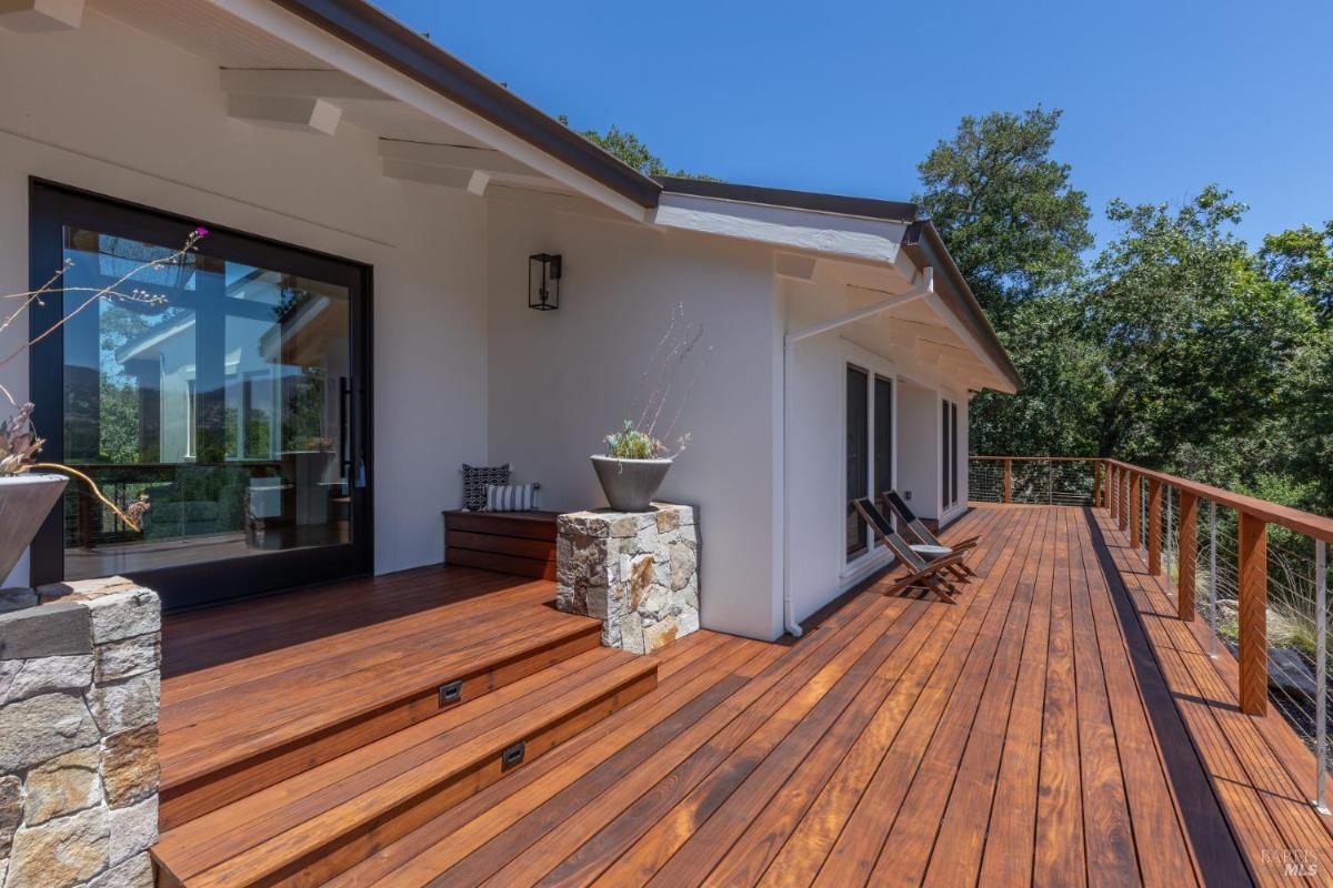 A wooden deck with railings and seating outside the house.