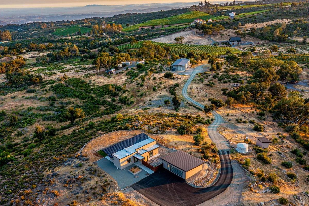 An aerial view of a modern home with surrounding vineyards and open countryside.