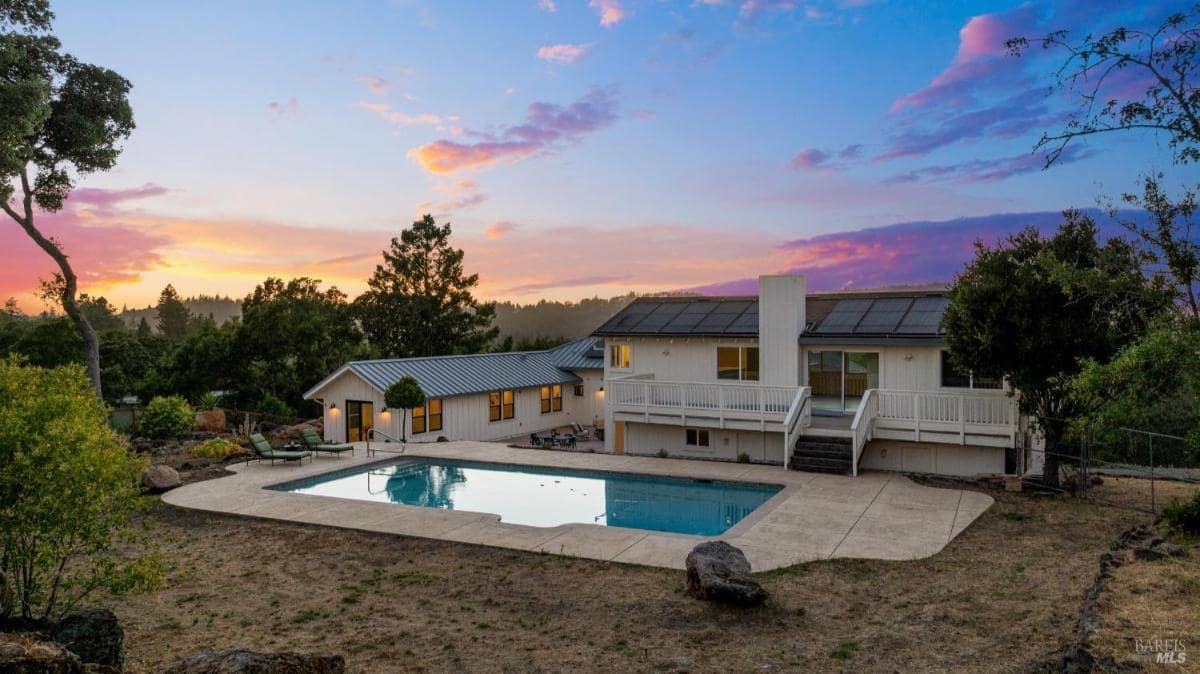 Backyard pool area with a view of the house during sunset.