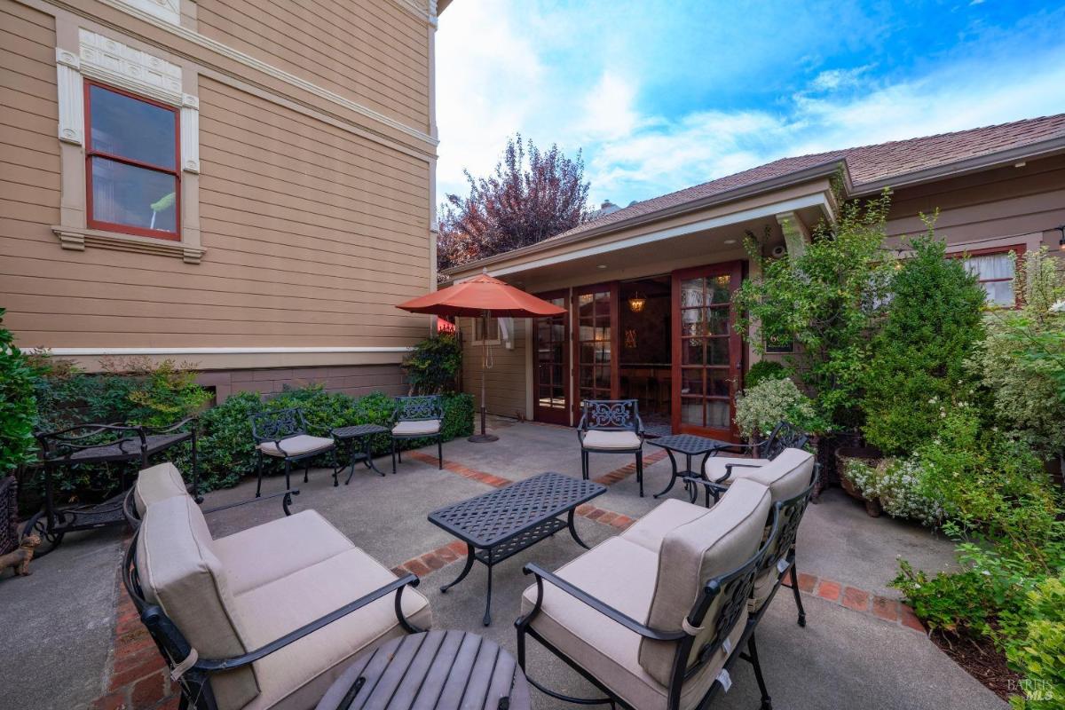 Outdoor patio with seating and an umbrella next to the house.