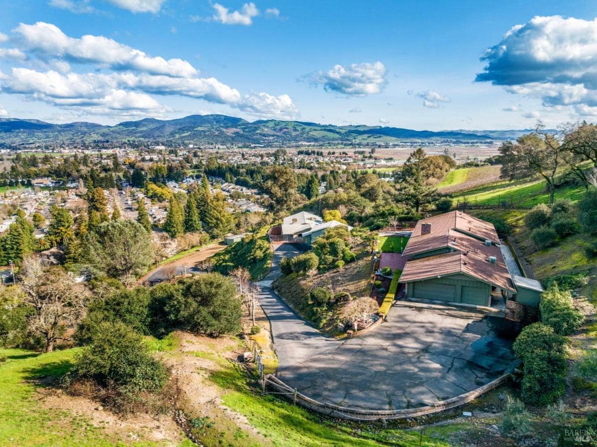 Elevated view of a property with multiple structures and a driveway.