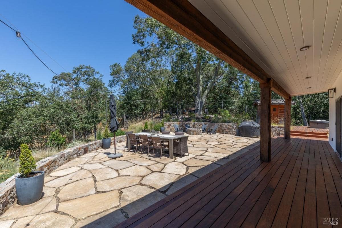 Outdoor dining area with stone patio and covered wooden deck.