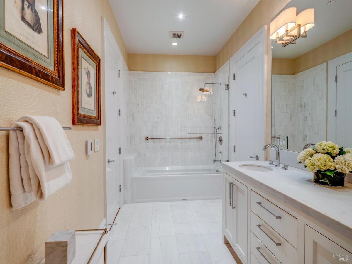 A bathroom with a tub-shower combo, white tiles, and framed wall art.