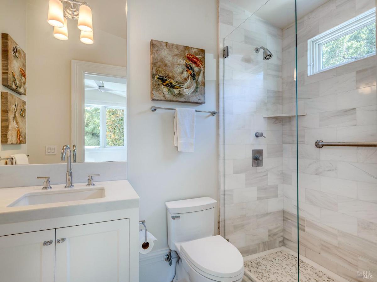 A bathroom with a glass-enclosed shower, white tiles, and minimal decor.