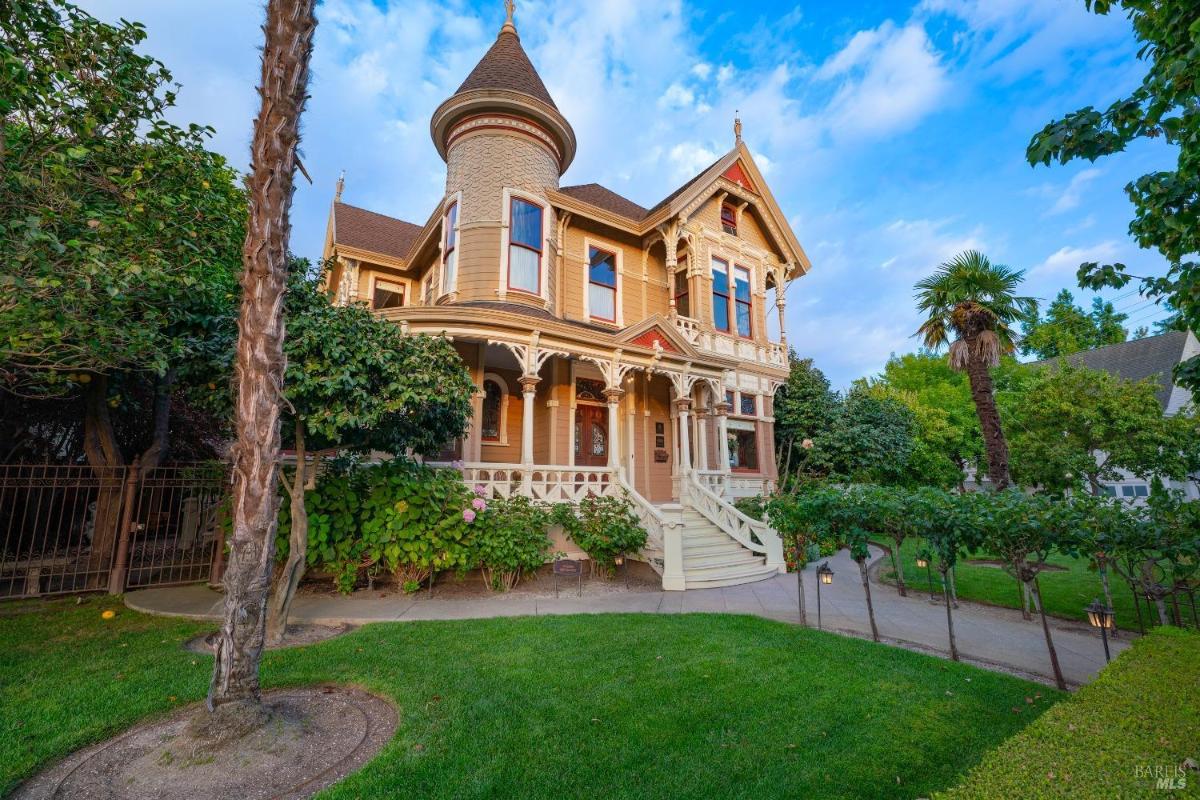 Side angle of a Victorian-style house with a tower and detailed trim.