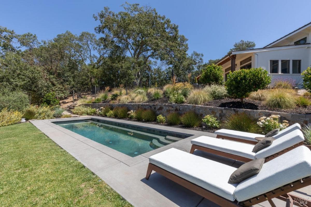 Rectangular swimming pool with lounge chairs and landscaped surroundings.