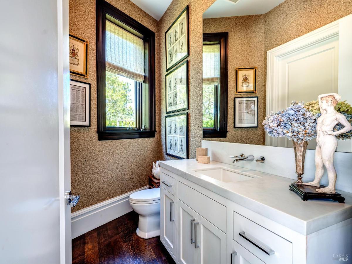 A powder room with a single vanity and large mirror next to a window.