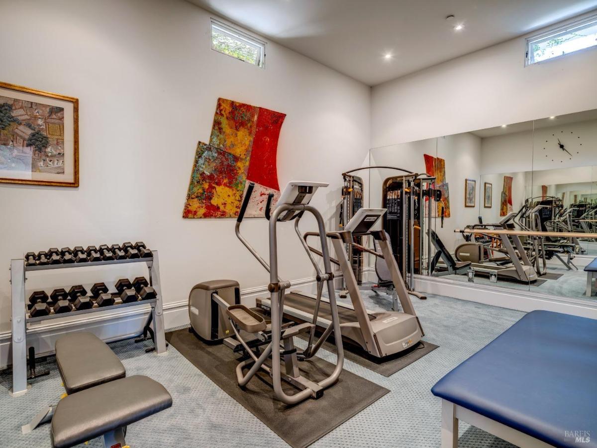 A home gym with exercise equipment, mirrors, and artwork on the walls.