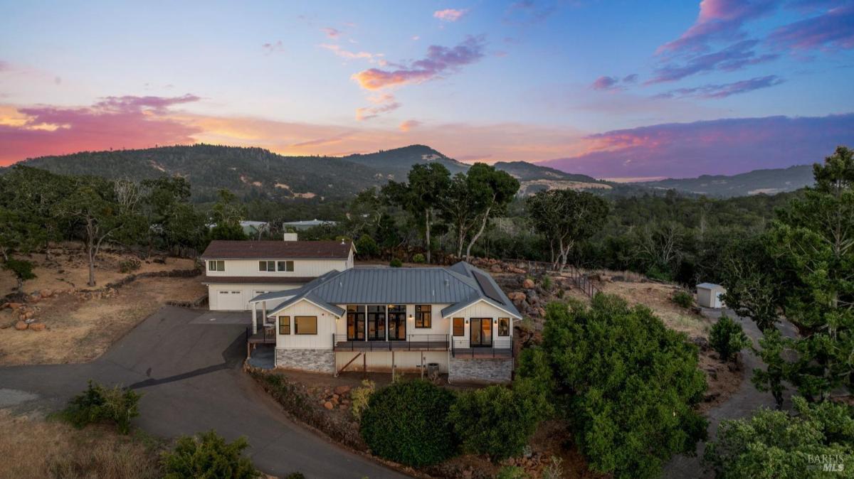 Aerial view of the property showing the house, pool, and surrounding trees.