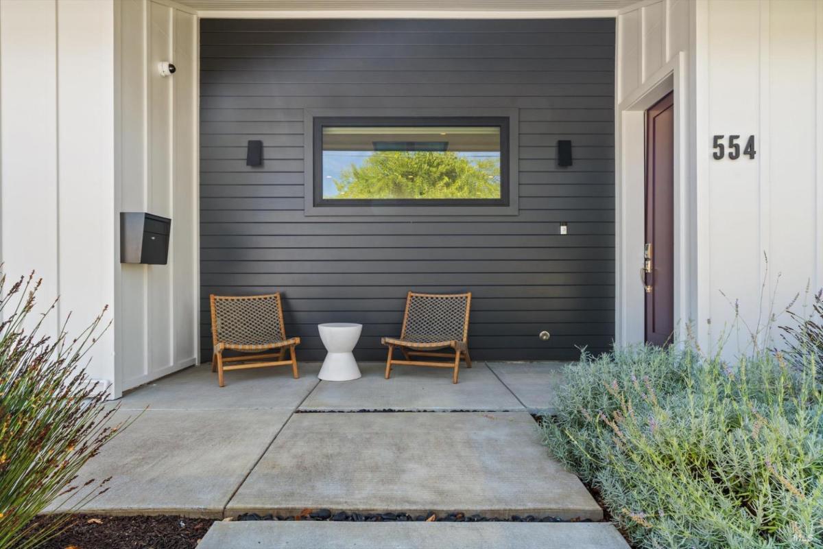 Front porch with two chairs, a small table, and a dark siding accent wall.