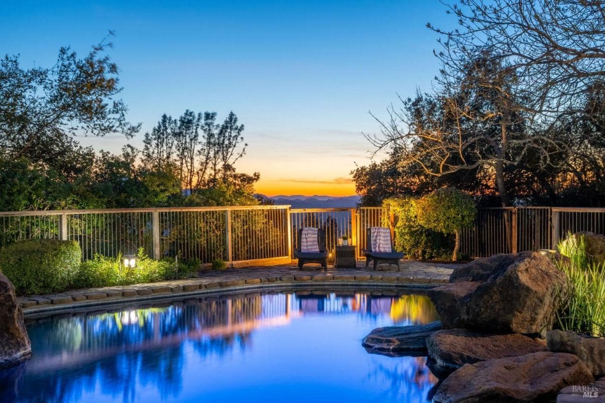 Wooden deck with outdoor seating and a view of the home at dusk.