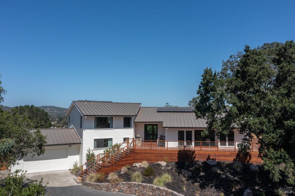 Front view of a house with solar panels and a wooden deck.