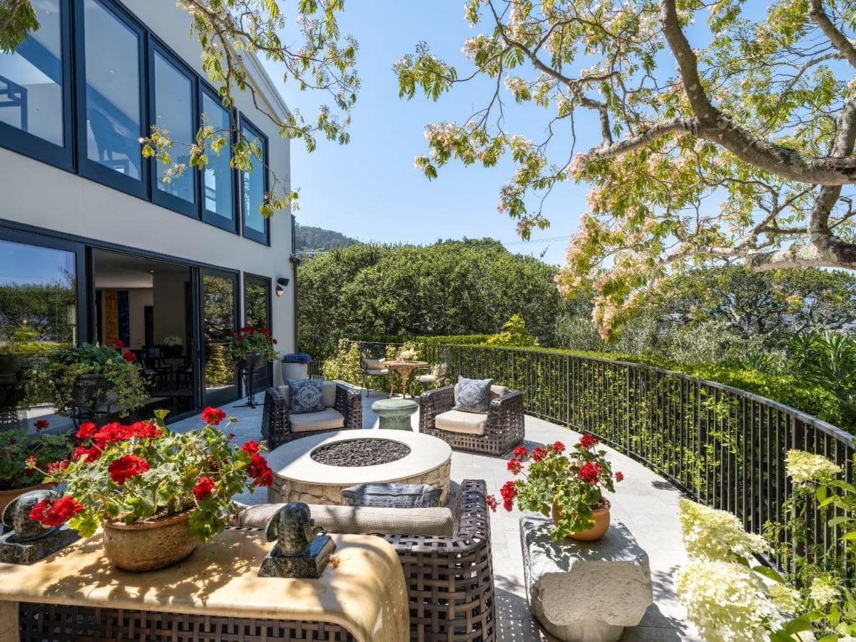 An outdoor seating area with a curved railing and lush greenery.