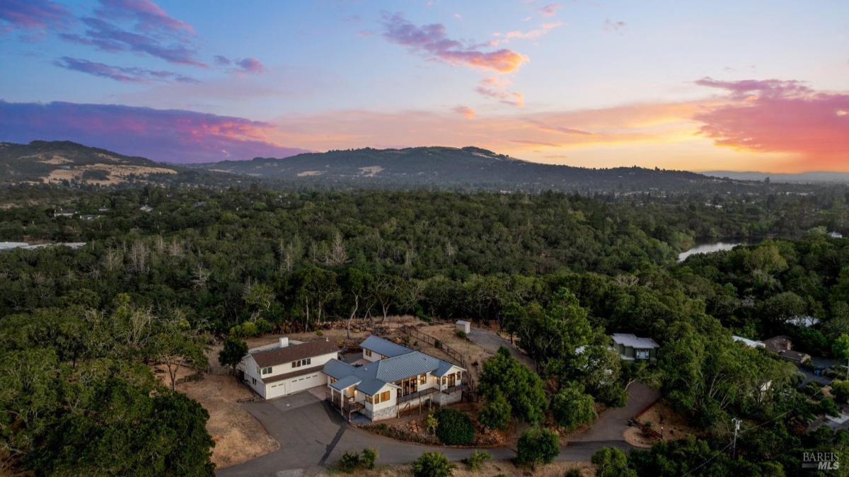 Distant aerial view of the property and nearby wooded area.