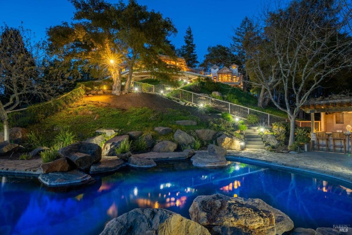 Hillside pool area with a landscaped pathway and lit surroundings.