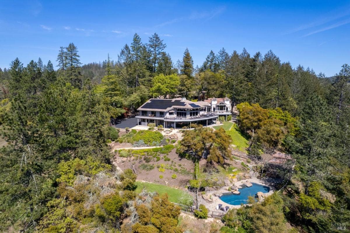 Aerial view of the hillside property with gardens and a pool.