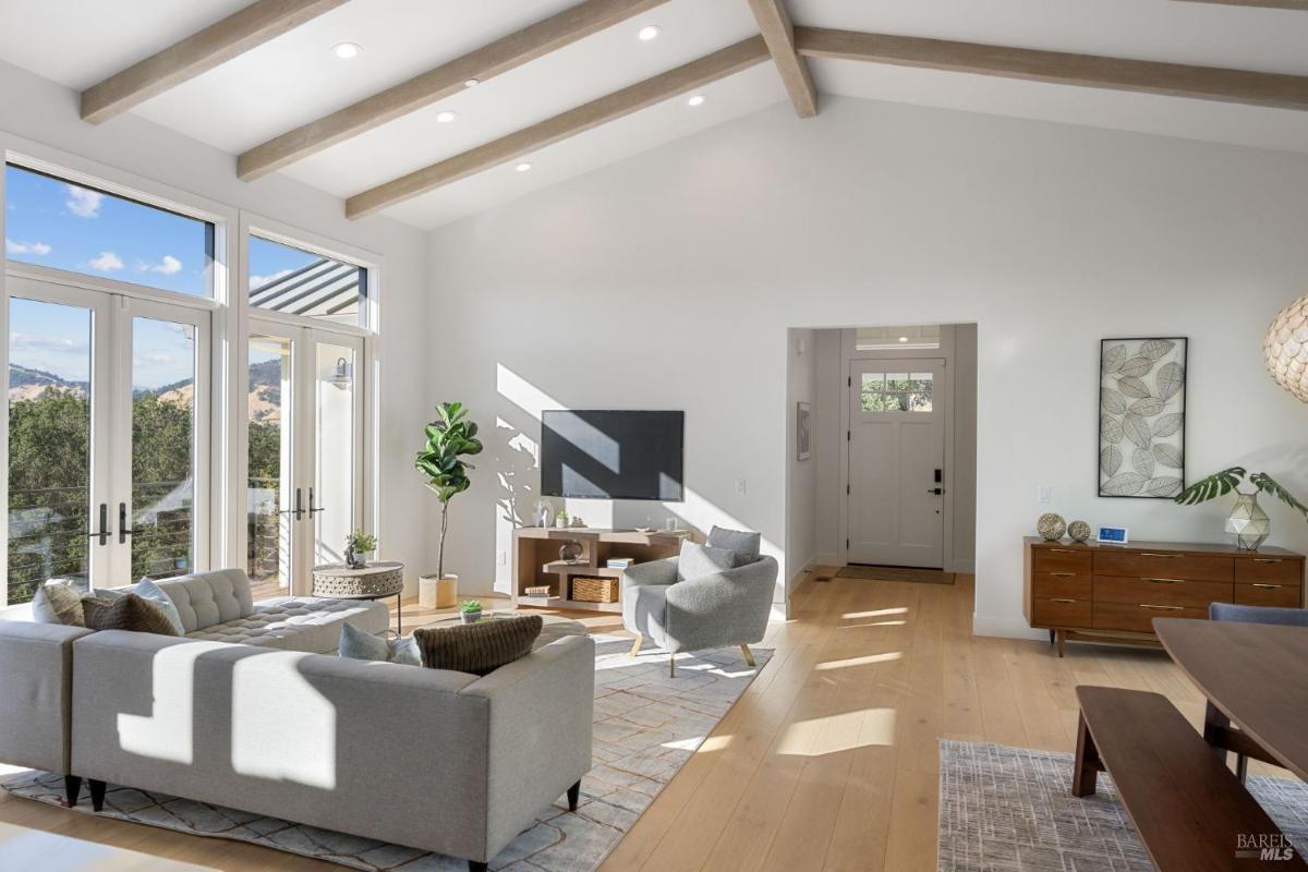 A bright living room with large windows and a view of surrounding hills.