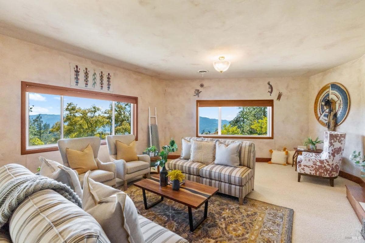 A bright sitting room with large windows and views of trees.