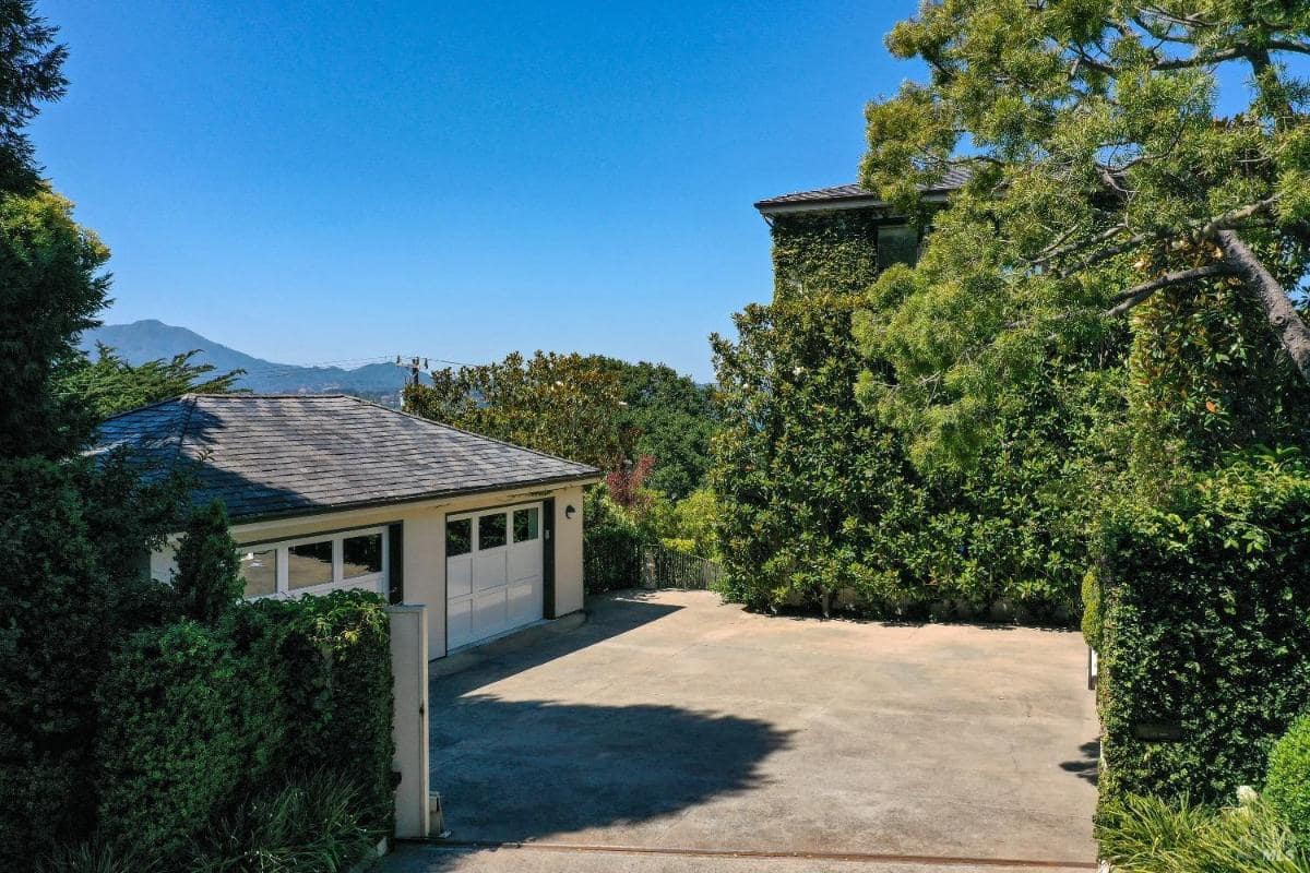 A driveway with a garage and surrounding trees.