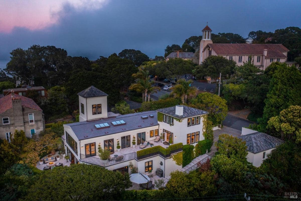 Aerial view of a large multi-level house surrounded by trees at twilight.