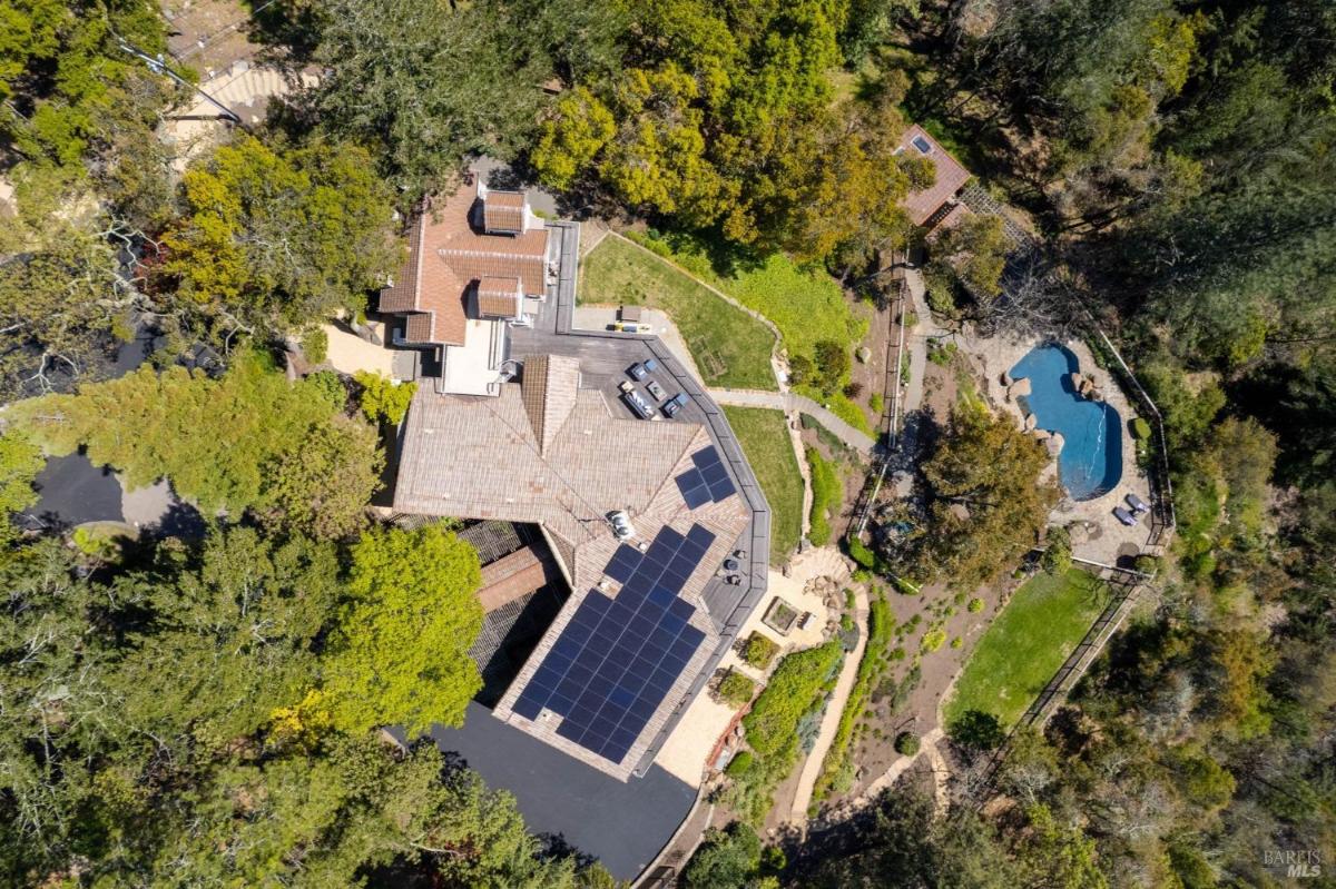 Solar panels on the roof of a home with a pool and landscaped yard.