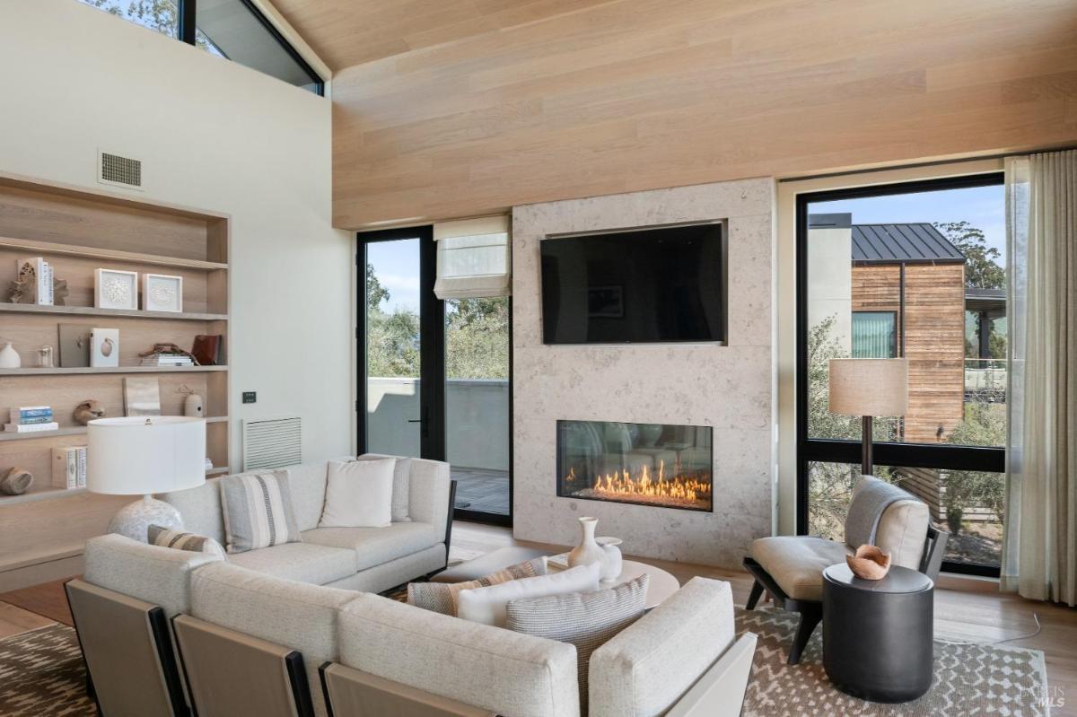 A cozy living room with a built-in fireplace, TV, and bookshelf.