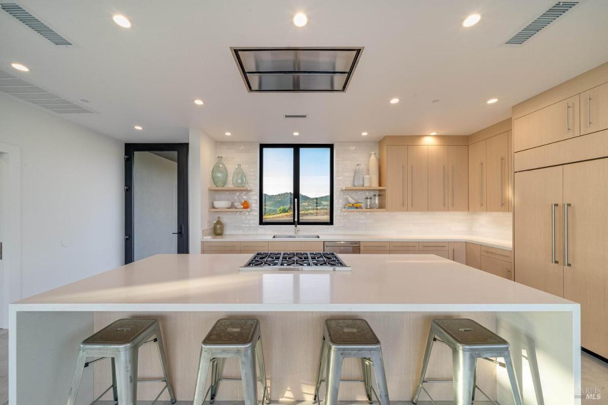 A kitchen with a large central island, built-in stovetop, and ample cabinetry.