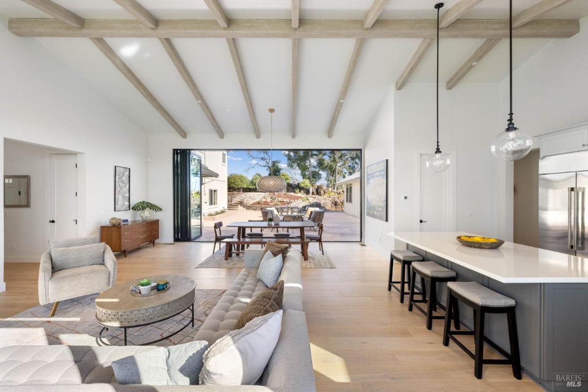 A combined kitchen and living area with a large dining table and island seating.