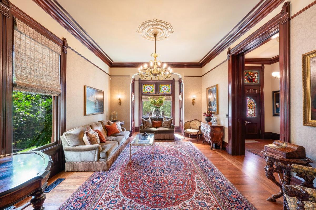 Living room with a large rug, stained glass windows, and seating area.