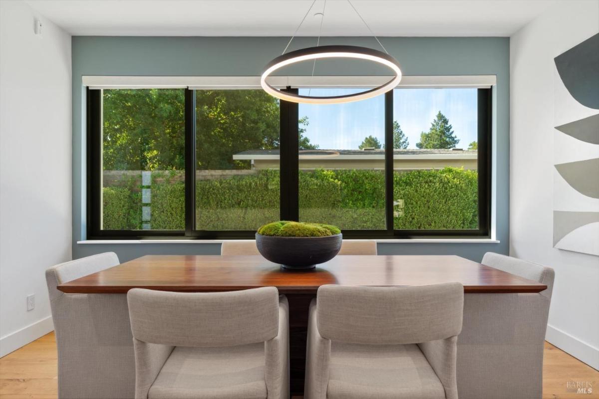 Dining area with a wooden table and large windows.