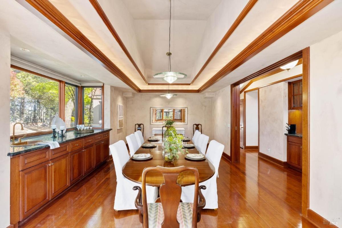 A dining room with a wooden table and chairs near large windows.