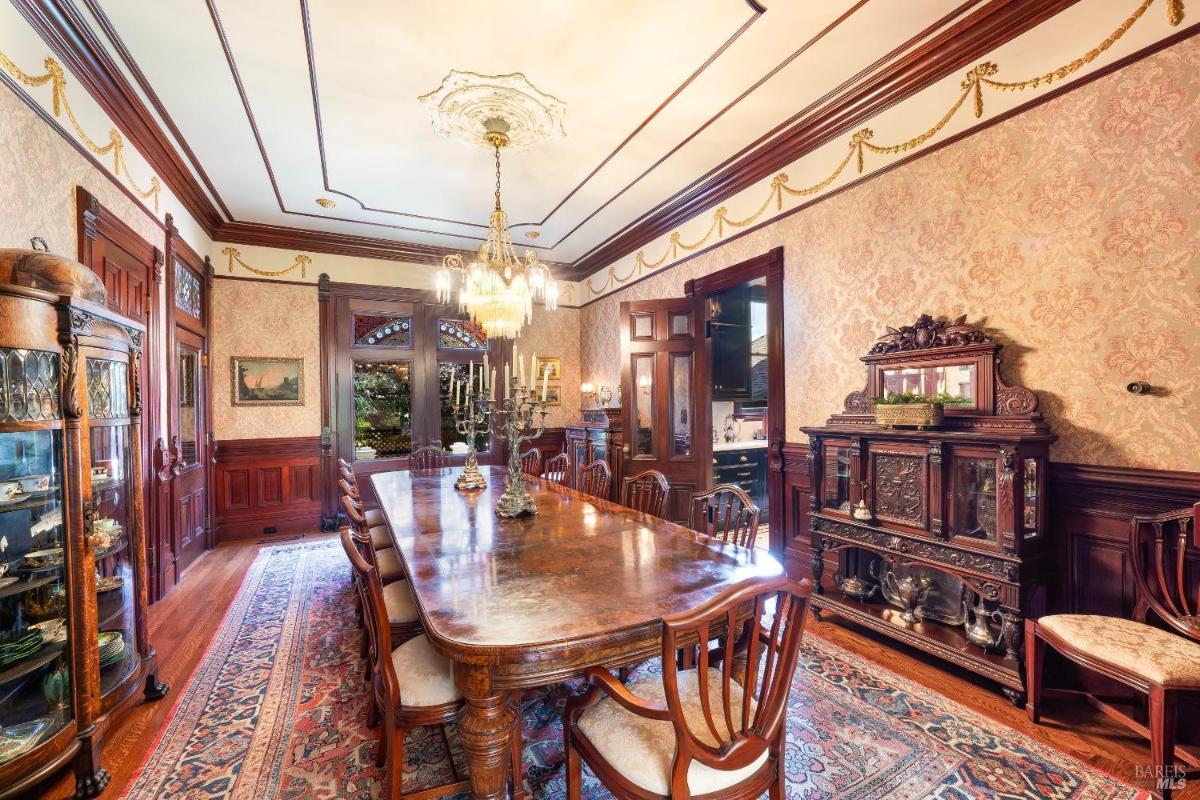 Dining room with a long table, chandelier, and decorative wood accents.