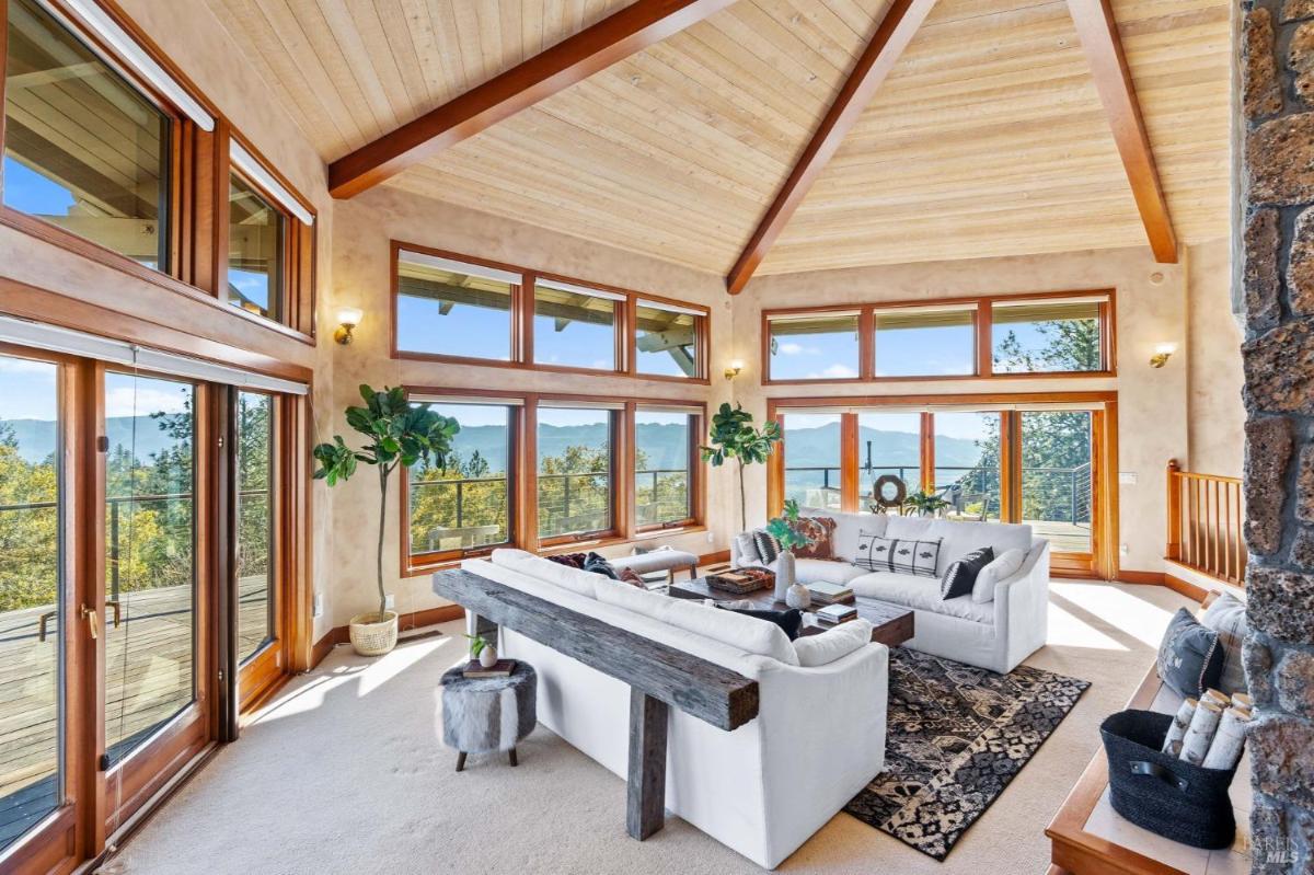 A living room with vaulted ceilings, stone fireplace, and large windows.