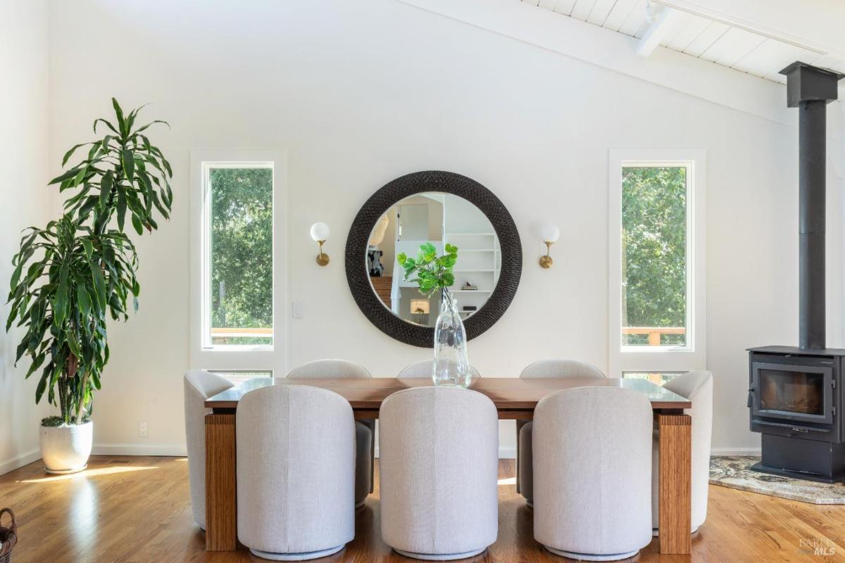 A dining room with a round table, chairs, and a wood-burning stove.