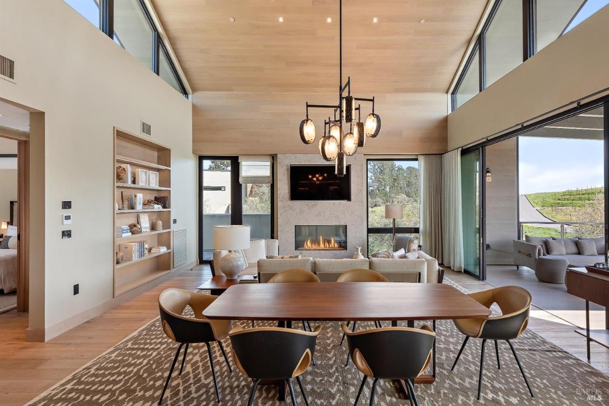 A dining area adjacent to the kitchen, featuring floor-to-ceiling windows and modern lighting.