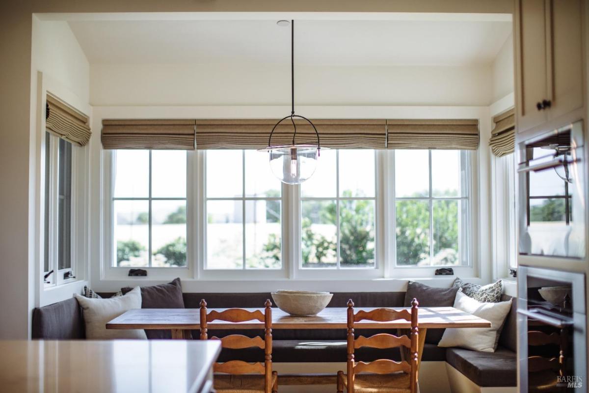 Breakfast nook with a table and built-in seating by large windows.