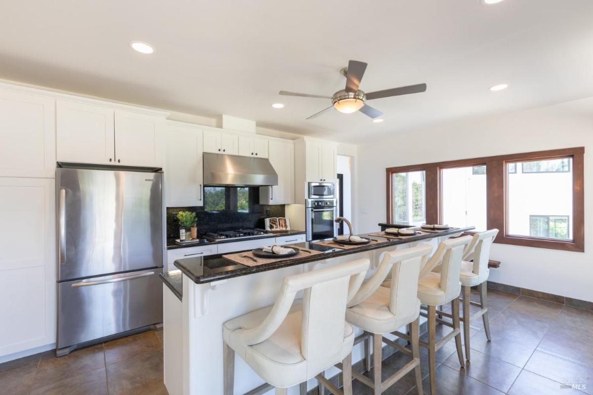 A kitchen with white cabinetry, stainless steel appliances, and a breakfast bar.